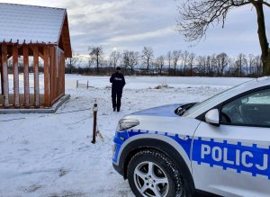 policjantka kontroluje zamarznięty staw, wokół zimowa sceneria, wiata i fragment radiowozu