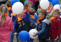 Grupa roześmianych dzieci z balonami.
