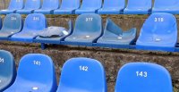Zdjęcie zniszczonych krzesełek na stadionie sportowym.