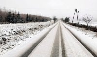 Na zdjęciu widoczne trudne warunki drogowe. Śnieg leżący na jezdni oraz w tle przyroda.
