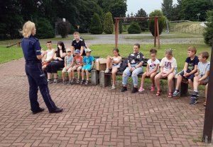 policjantka rozmawia z grupą dzieci na temat bezpiecznego wypoczynku w trakcie letniego wypoczynku