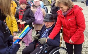 Kolorowe zdjęcie jak policjantka wręcza odblask osobom starszym