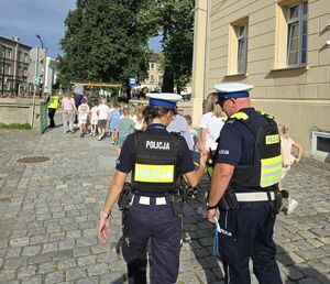 kolorowe zdjęcia na których widać Policjantów oraz Stażników Miejskich uczących pierwszoklasistów korzystać z przejścia dla pieszych. Rozmowy w klasie oraz praktyka na zewnątrz