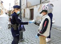 Sierż. Prudek oraz policjantka rozdaje maseczki mieszkańcom Głogówka.