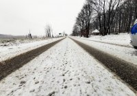 Na zdjęciu widoczne trudne warunki drogowe. Śnieg leżący na jezdni oraz w tle przyroda.