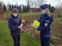 Policjantka na terenie kompleksów działkowych rozmawia z kobietą oraz wręcza materiały profilaktyczne.