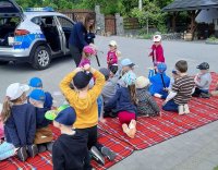 grupa dzieci siedząca na kocu słucha prelekcji policjantki