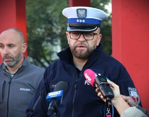 zdjęcie kolorowe: policjanci rozdają dzieciom kaski i elementy odblaskowe